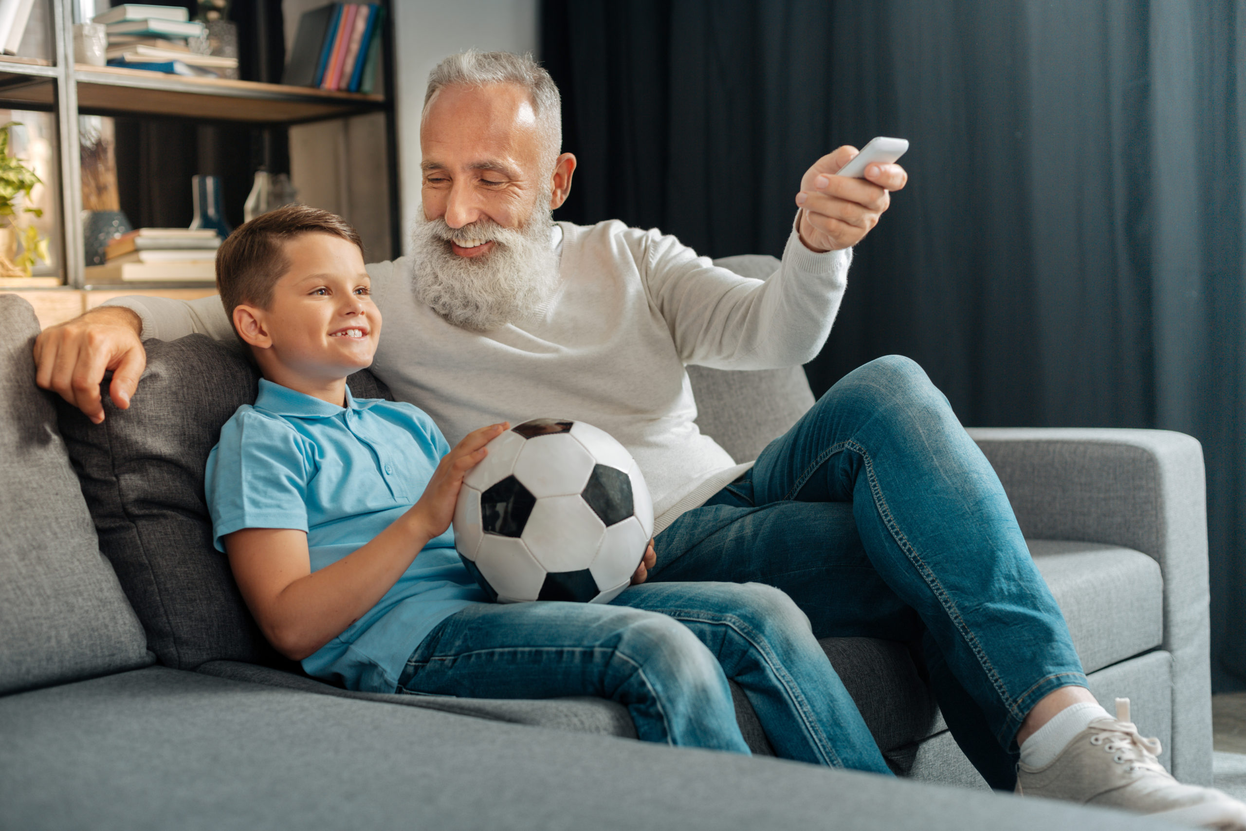 Man turning air conditioning on while watching football with grandson