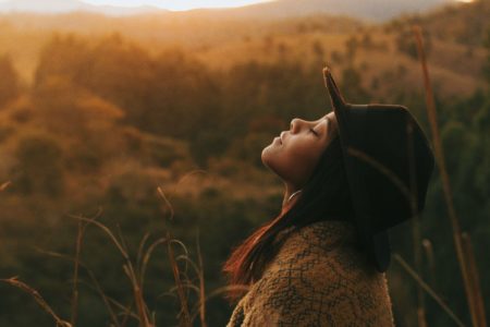 woman wearing black hat facing towards the sky with her eyes closed