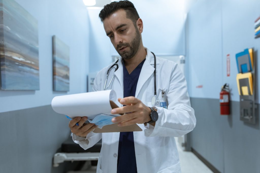 doctor with a serious face is holding a white notepad