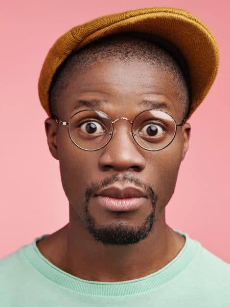 Shocked black African American male driver realizes that his car is brocken, has no instruments for repairing, stares at camera with bugged eyes, needs to reach destination in nearest future.