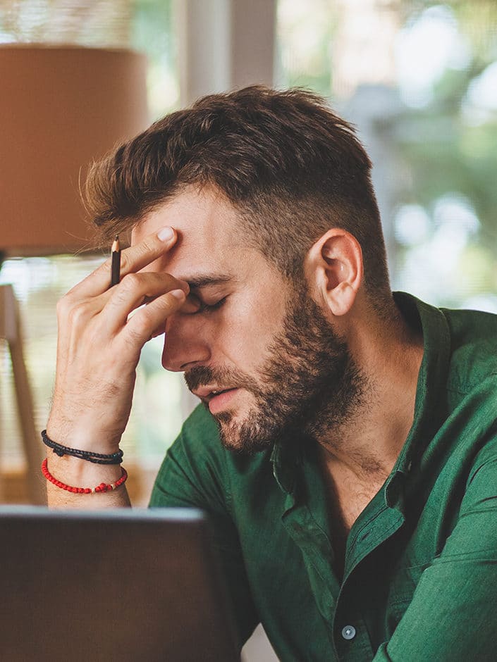 Adult man with hand on his head due to headache and other mental health issues.