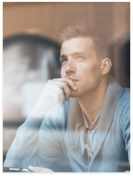 Young man staring out the window concept image for outpatient programs
