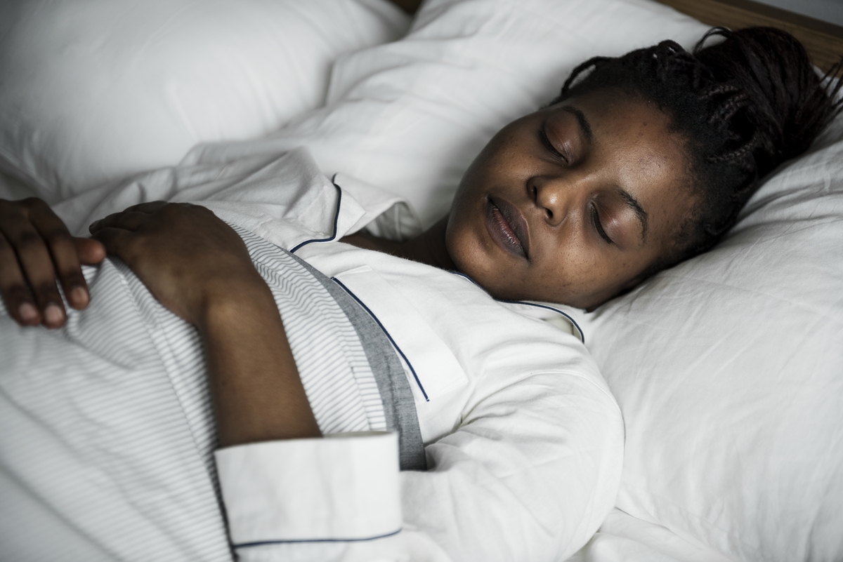 young woman resting in bed in dark room with neon lights|