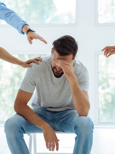 Depressed man encircled by caring hands, symbolizing support from mental health Georgetown