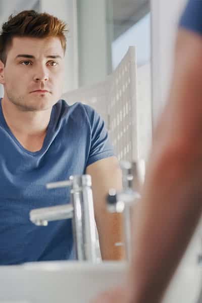 Young man with personality disorder looking at the mirror.