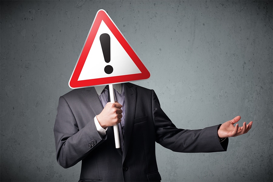 Man holding an exclamation sign covering his face. Man anxiously waiting for a reply; lack of response can be a BPD trigger potentially leading to suicidal behavior