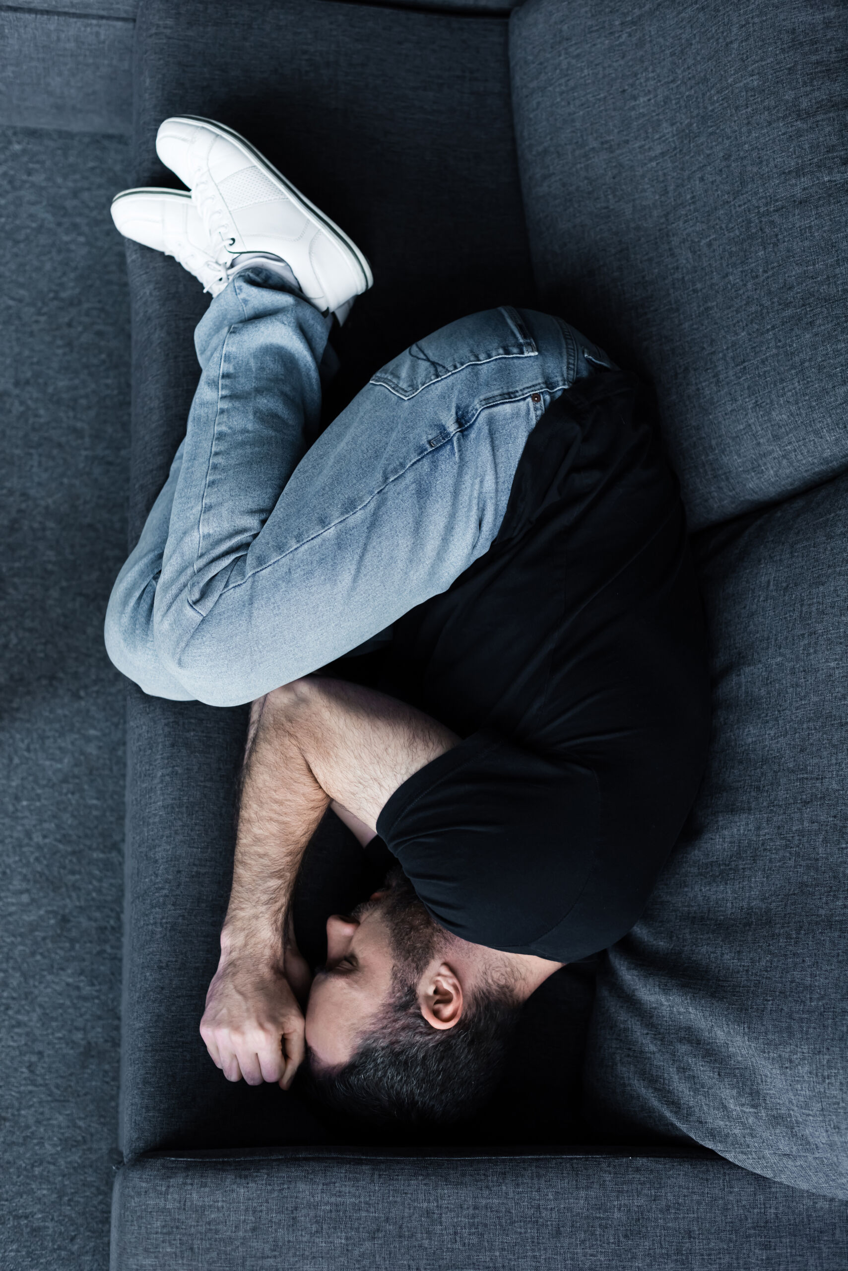 Young man lying in a fetal position on the couch