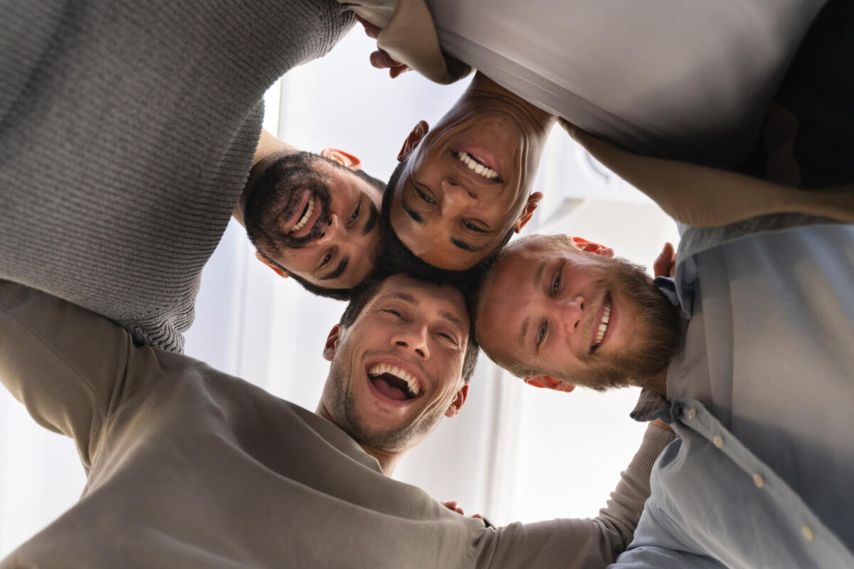 Group of men leaning in together laughing in a fun and energetic group moment