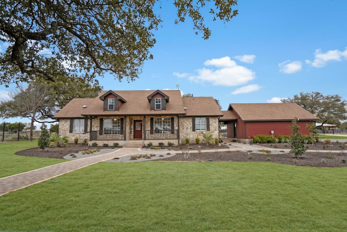Exterior of a single-story home with a large green lawn and mature trees