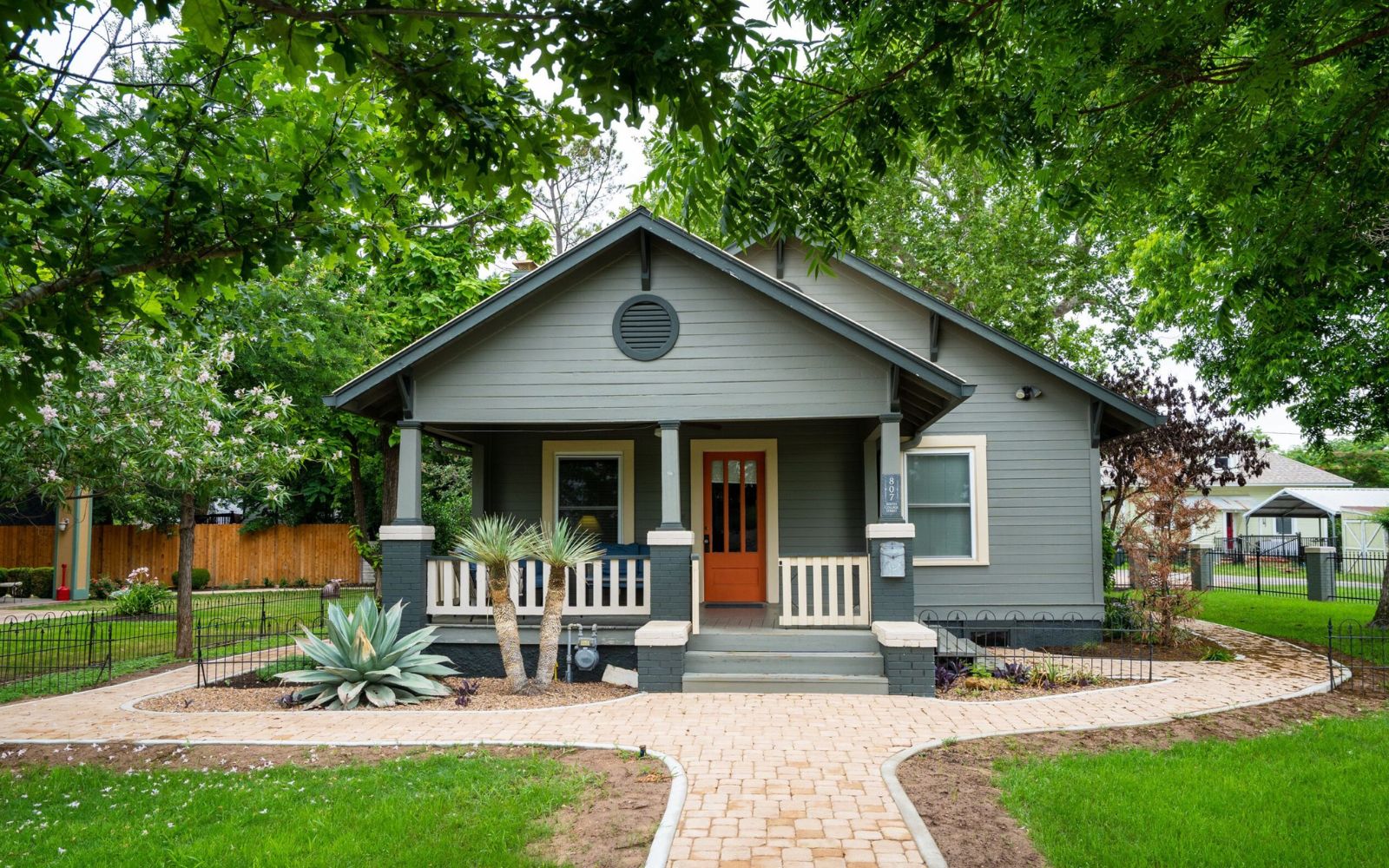 Exterior of a charming single-story bungalow with a green lawn and inviting front porch