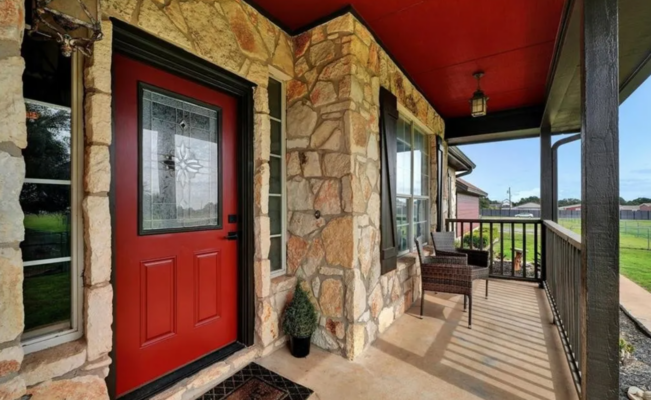 Exterior of a stone and wood building with a red door and warm architectural details