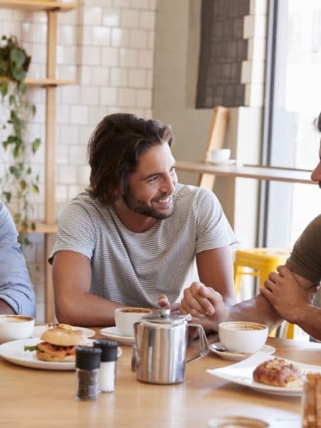 Man sitting at a table with food and a drink in a casual dining or cafe setting