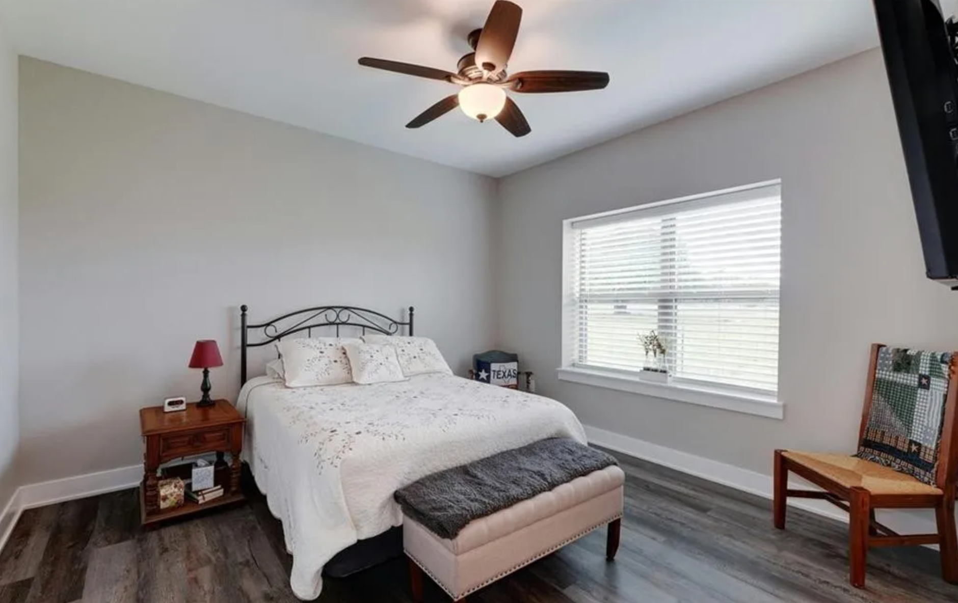 Bedroom with a black metal bed frame, ceiling fan, and natural window light