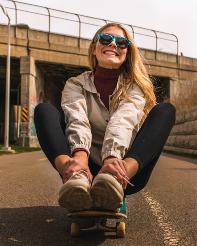a woman sitting on skateboard in a street smiling