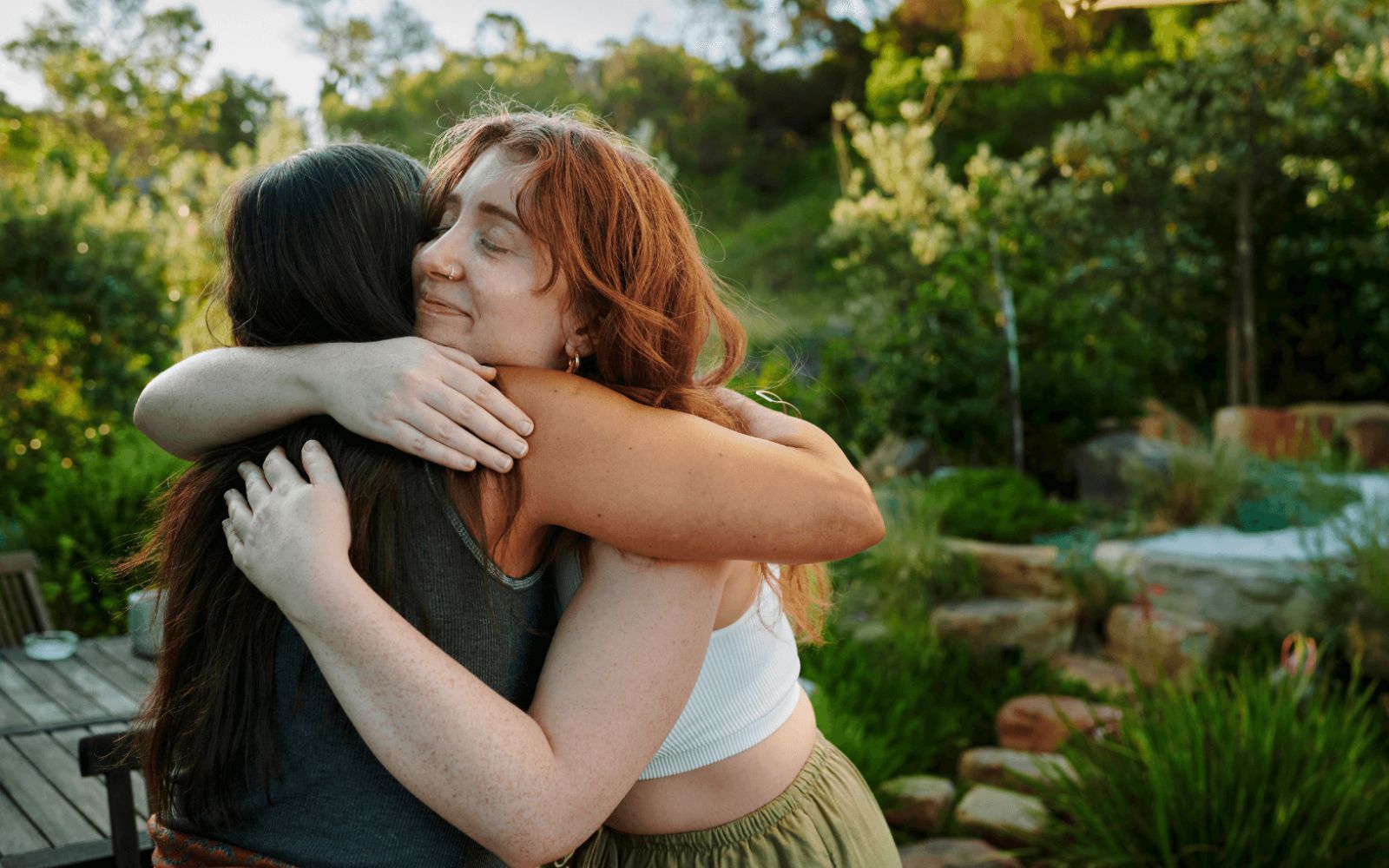 Two people embracing warmly in a green outdoor setting