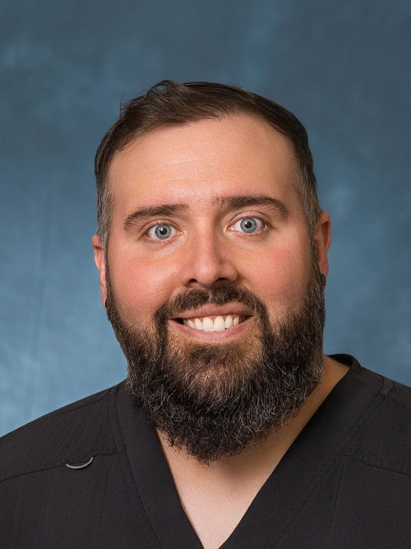 Man with a beard and friendly smile posed against a dark background