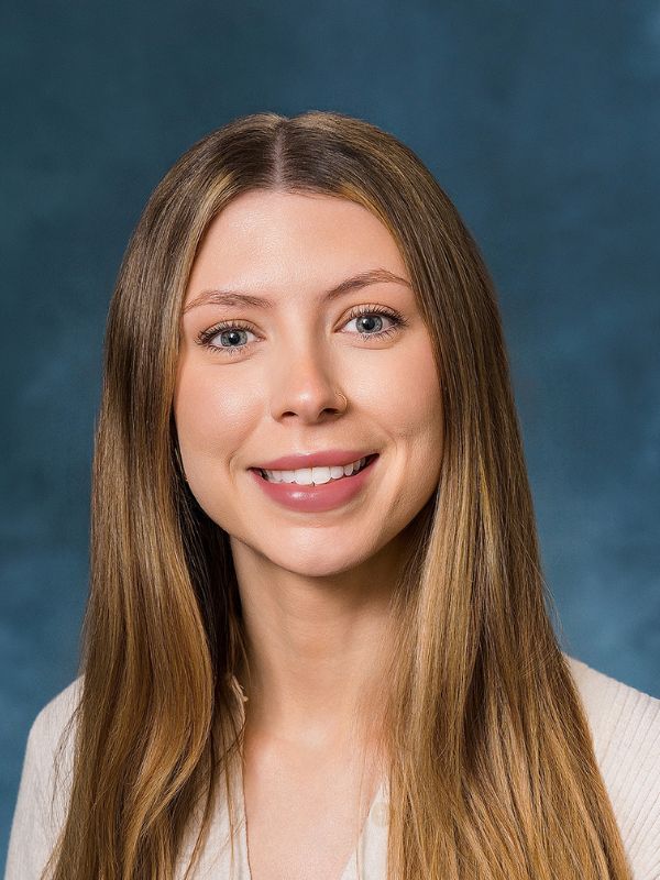 Young woman with long blonde hair smiling softly against a neutral background